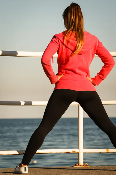 Mujer jogger se extiende en el muelle por la playa —  Fotos de Stock