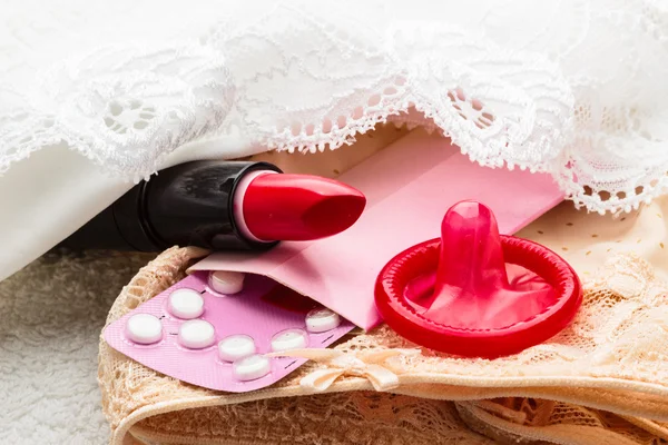 Таблетки презерватив і помада на мереживному білизні — стокове фото