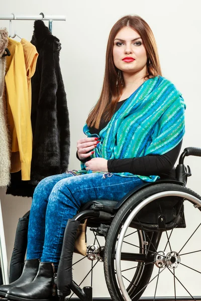 Invalid girl on wheelchair choosing clothes in wardrobe