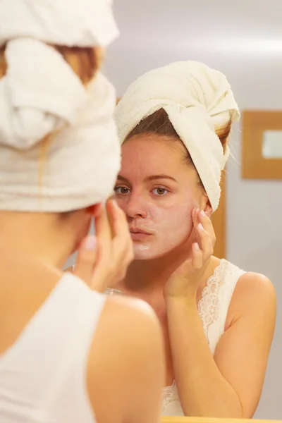 Mulher aplicando creme máscara no rosto no banheiro — Fotografia de Stock