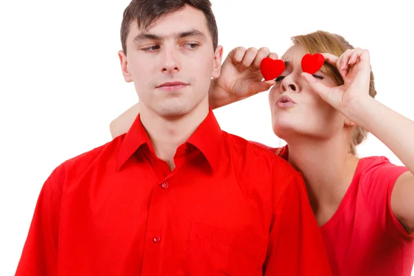 Serious man and crazy woman holds red hearts over eyes — Stock Photo, Image