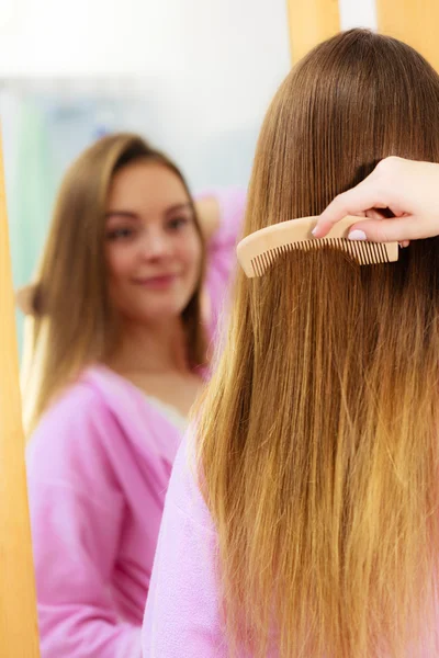 Mujer peinando su pelo largo en el baño — Foto de Stock