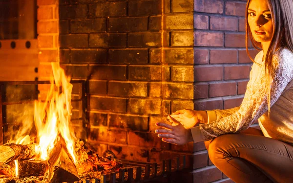 Vrouw handen opwarmen bij open haard. Winter huis. — Stockfoto