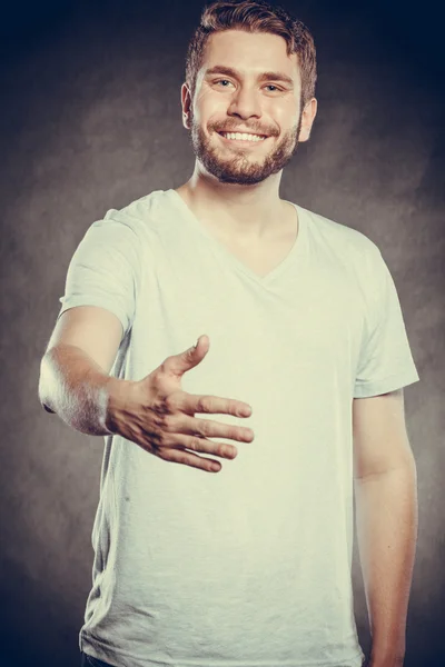 Jovem sorridente oferecendo palma de mão para aperto de mão — Fotografia de Stock