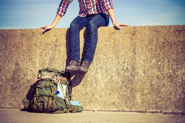 Mann touristischer Backpacker sitzt auf Grunge-Wand im Freien — Stockfoto