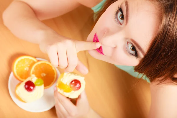 Woman eating cake showing quiet sign. Gluttony. — Stock Photo, Image