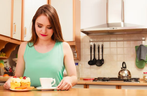 Woman with coffee and cake in kitchen. Gluttony. — Stock Photo, Image