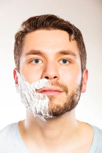 Man with shaving cream foam on half of face. — Stock Photo, Image