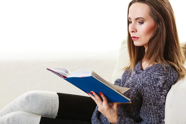Kobieta siedząca na kanapie czytająca książkę w domu — Zdjęcie stockowe