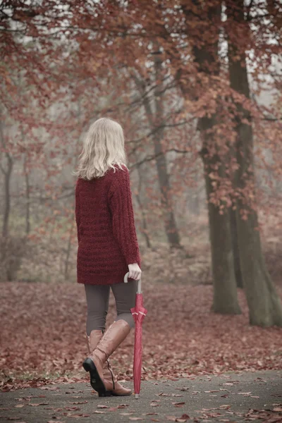 Mode vrouw met paraplu ontspannen in vallen park. — Stockfoto