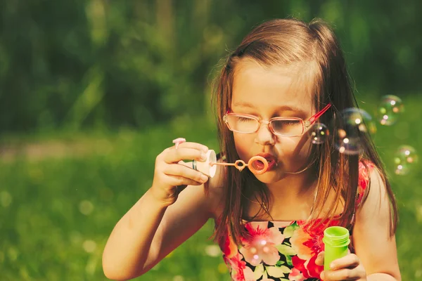 Niña soplando burbujas de jabón al aire libre . —  Fotos de Stock