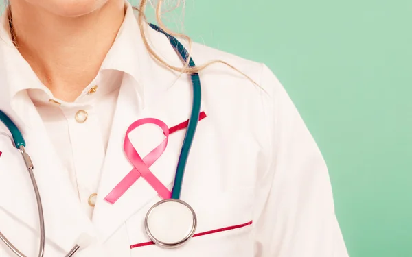 Pink ribbon with stethoscope on medical uniform. — Stock Photo, Image