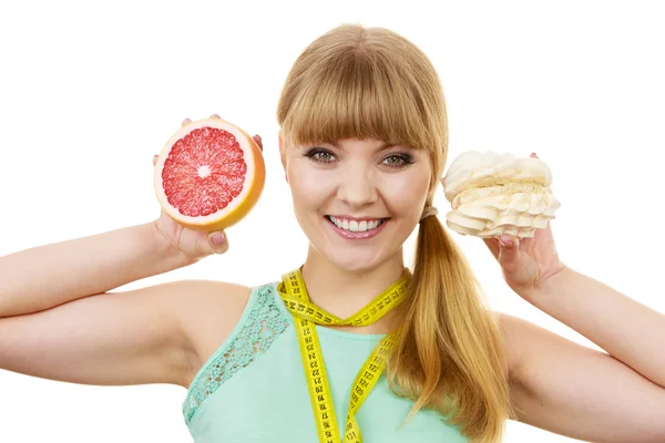 Женщина выбирая фрукты или торт сделать диетический выбор — стоковое фото