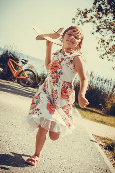 Niña en la playa con avión de avión de papel — Foto de Stock