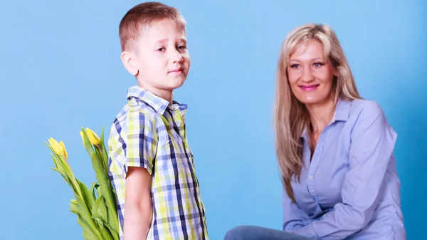 Niño pequeño con madre sostener flores detrás de la espalda . —  Fotos de Stock