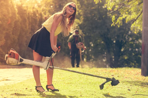 Menina com cortador de grama no parque — Fotografia de Stock