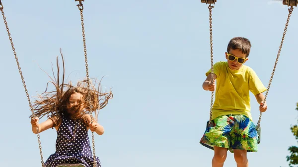 Dwoje dzieci zabawy na swingset. — Zdjęcie stockowe