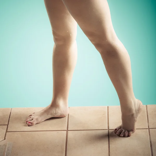 Female exposed legs stand at edge swimming pool. — Stock Photo, Image