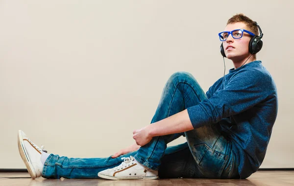 Joven con auriculares sentado en el suelo — Foto de Stock