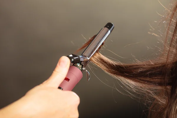 Estilista rizando el pelo para mujer joven. — Foto de Stock