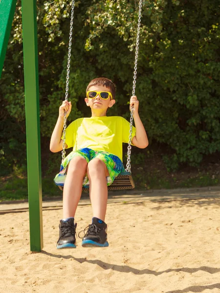 Boy playing swinging by swing-set. — Stock Photo, Image