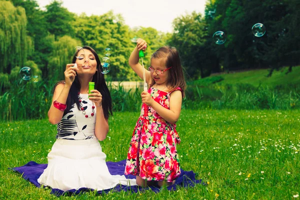 Mother and child blowing soap bubbles outdoor. — Stock Photo, Image