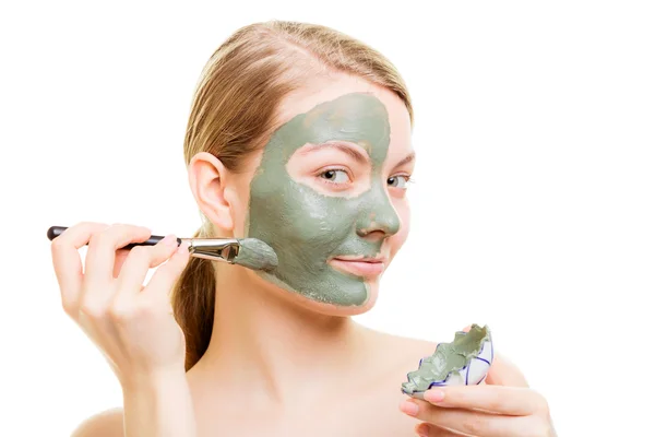 Chica aplicando mascarilla de arcilla facial en su cara — Foto de Stock