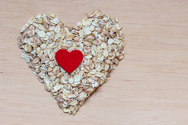 Oat flakes cereal heart shaped on wooden surface. — Stock Photo, Image