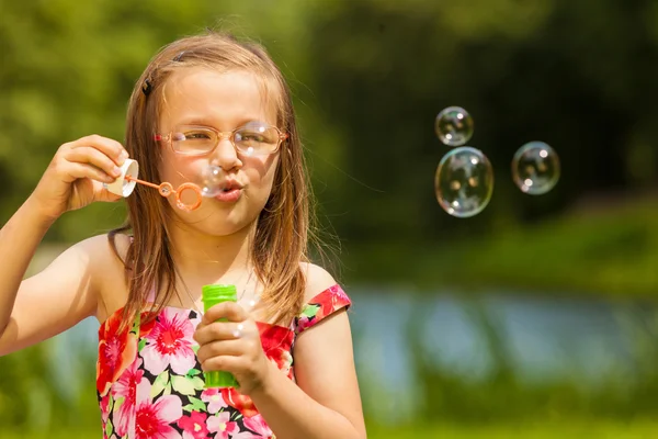 Kleines Mädchen Kind pustet Seifenblasen im Freien. — Stockfoto