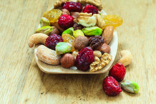 Varieties of dried fruits and nuts on wooden spoon. — Stock Photo, Image