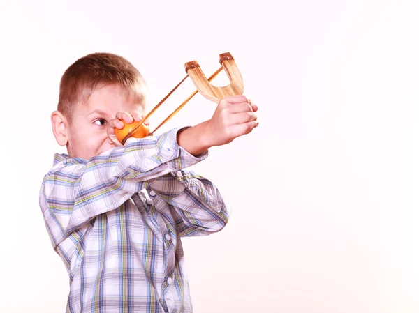 Jonge jongen gebruik sling shot schieten Mandarijn. — Stockfoto