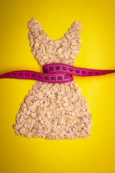 Dress shape made from oatmeal with measuring tape — Stock Photo, Image