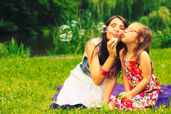 Mother and child blowing soap bubbles outdoor. — Stock Photo, Image