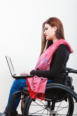 Young girl on wheelchair surfing web. clipart