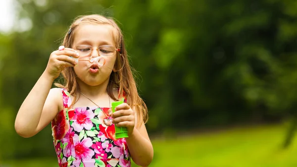 Lilla flickan barnet blåser såpbubblor utomhus. — Stockfoto