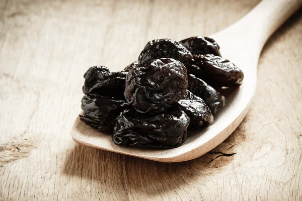 Dried plums prunes on wooden spoon — Stock Photo, Image