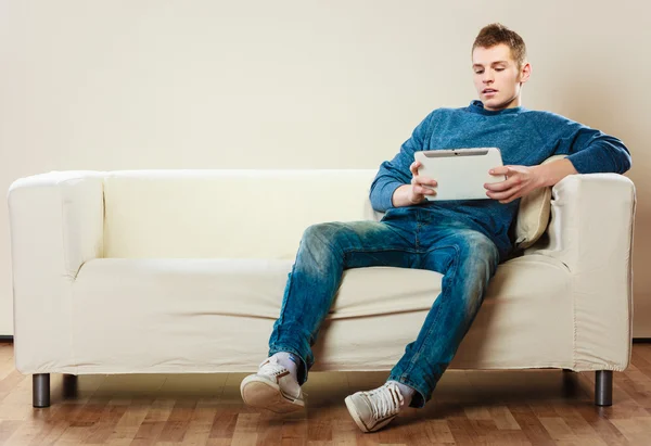 Junger Mann mit Tablet sitzt zu Hause auf Couch — Stockfoto