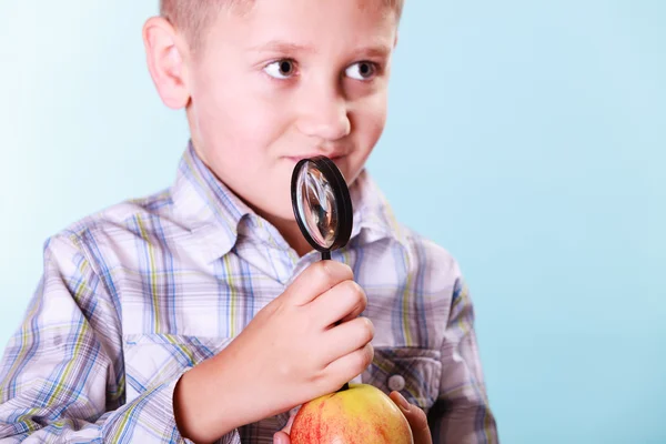 Kid examinar maçã com lupa . — Fotografia de Stock