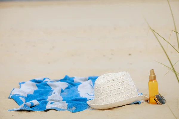 Beach set hat and sunscreen lotion lying on sand — Stock Photo, Image