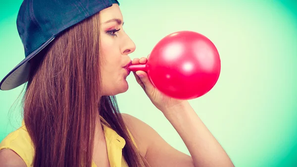 Girl blowing red balloon — Stock Photo, Image