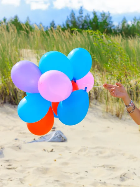 Mano sosteniendo globos en playa al aire libre —  Fotos de Stock