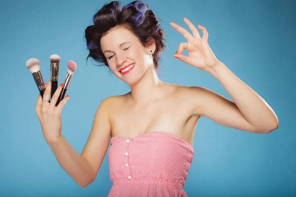 Женщина в роликах для волос держит щетки для макияжа — стоковое фото