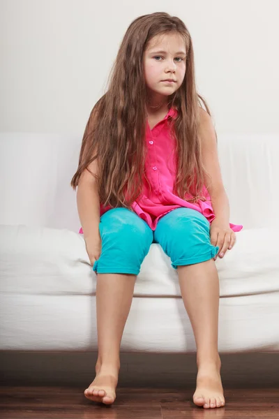 Sad unhappy little girl kid sitting on sofa. — Stock Photo, Image