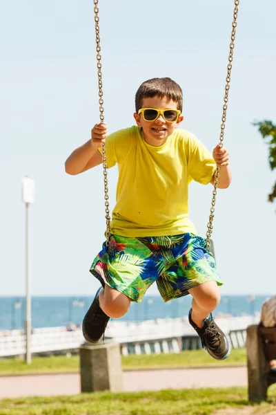 Pojken spelar svängande av swing-set. — Stockfoto