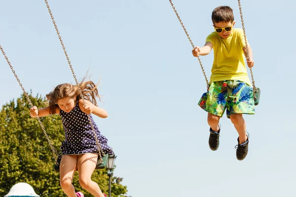 Dwoje dzieci zabawy na swingset. — Zdjęcie stockowe