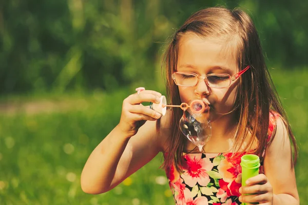 Lilla flickan barnet blåser såpbubblor utomhus. — Stockfoto