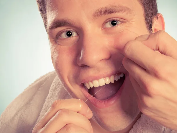若い男がデンタルフロスと彼女の白い歯のクリーニング — ストック写真
