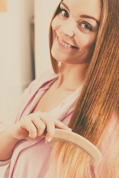 Mulher penteando seu longo cabelo liso — Fotografia de Stock