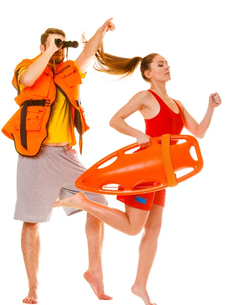 Lifeguards in life vest with rescue buoy running — Stock Photo, Image