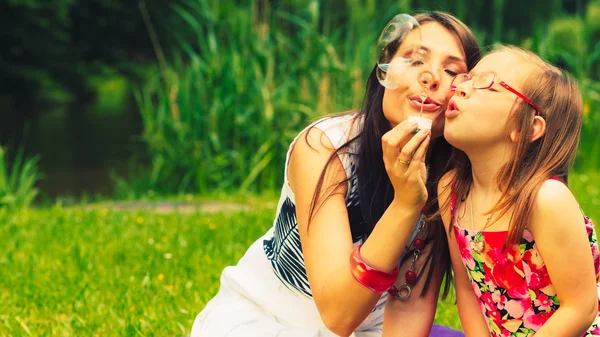 Mother and child blowing soap bubbles outdoor. — Stock Photo, Image